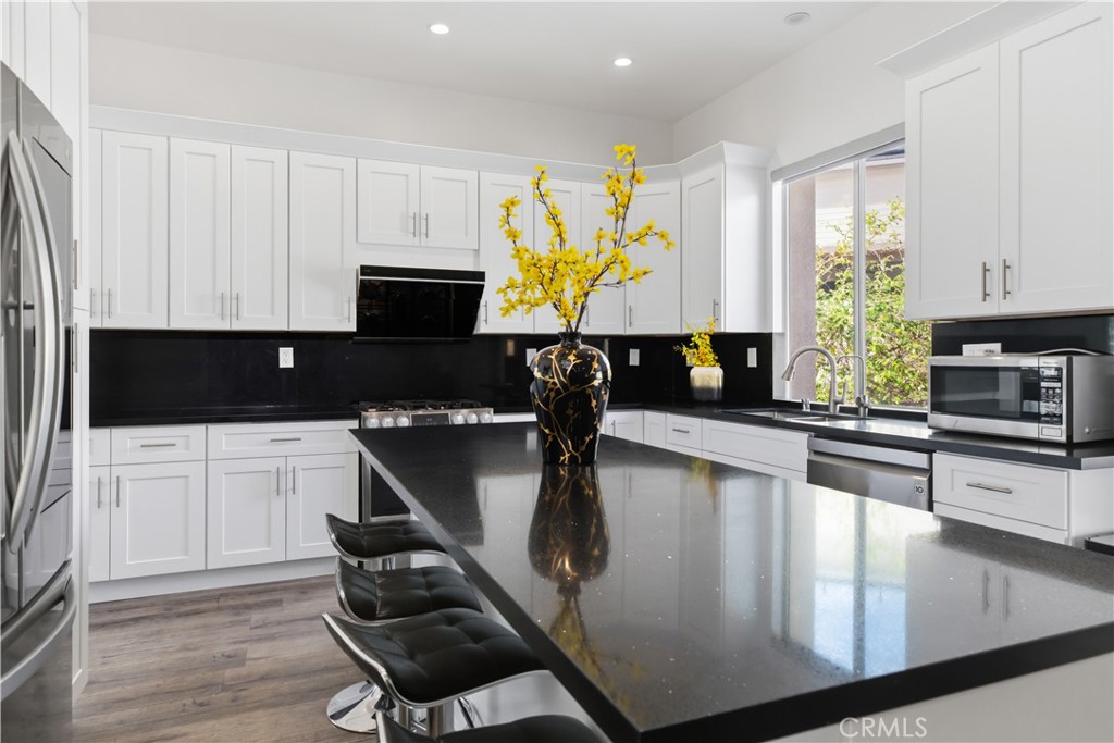 Bright kitchen with white cabinets, black countertops, and a large island with bar stools.
