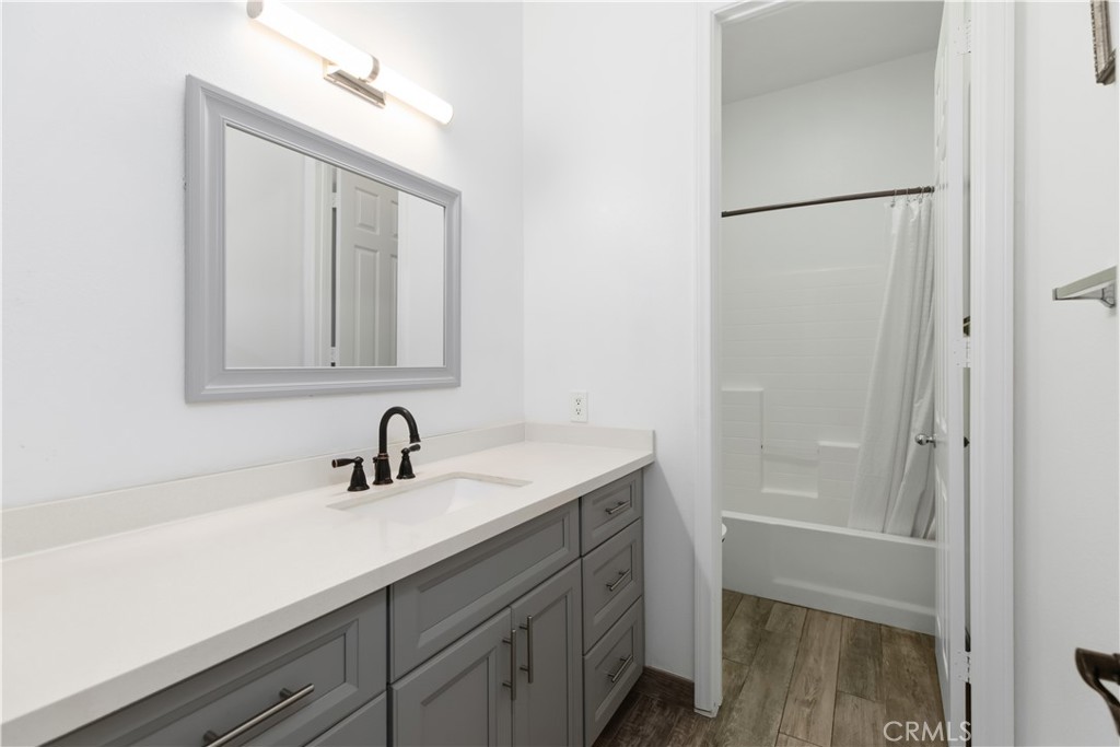 Bathroom with a gray vanity, black faucet, and bathtub behind the doorway.