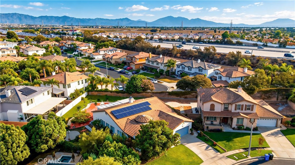 Aerial view of a tile-roofed home with solar panels, surrounded by Rancho Cucamonga homes and mountains.
