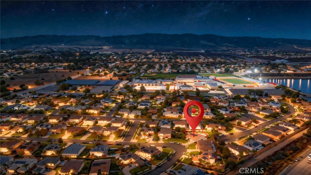 Aerial view of a residential neighborhood at night, with a red pin marking the property.