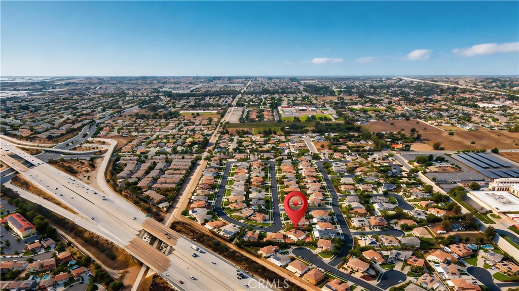 Aerial neighborhood view with a red pin marking the property beside a freeway.