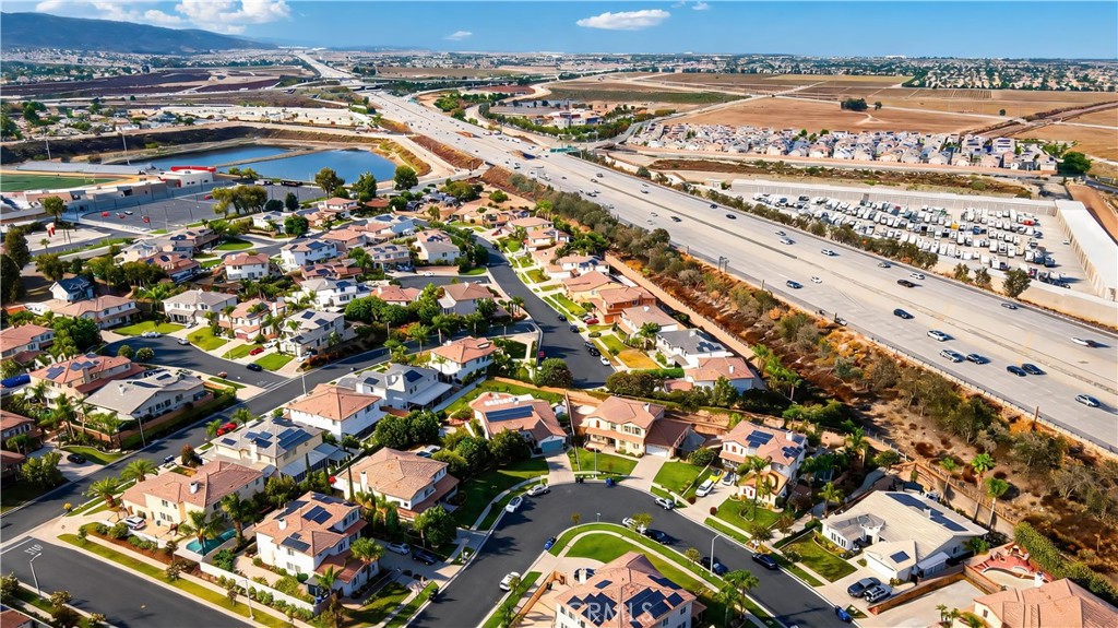 Aerial view of homes around a cul-de-sac beside a major freeway, with distant hills.