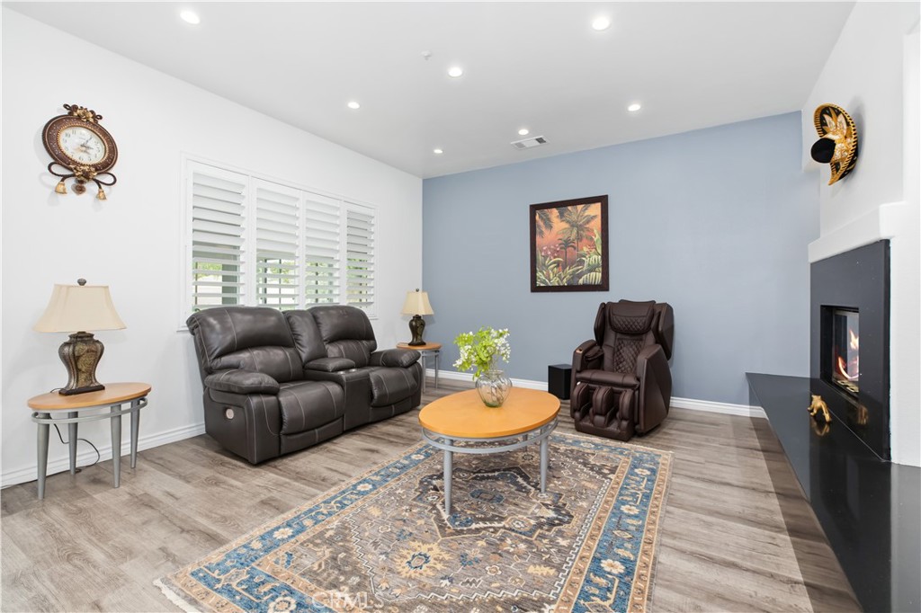 Living room with a gray leather sofa, massage chair, blue accent wall, and lit fireplace.
