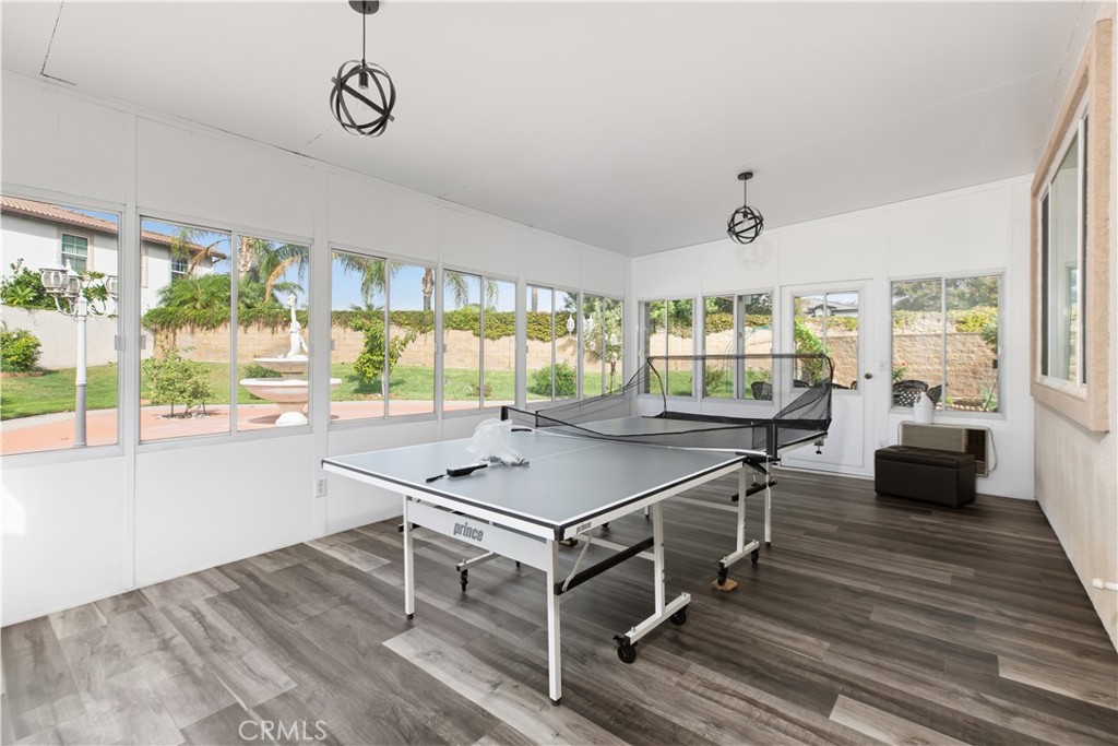 Enclosed game room with a ping-pong table and expansive windows overlooking the backyard.