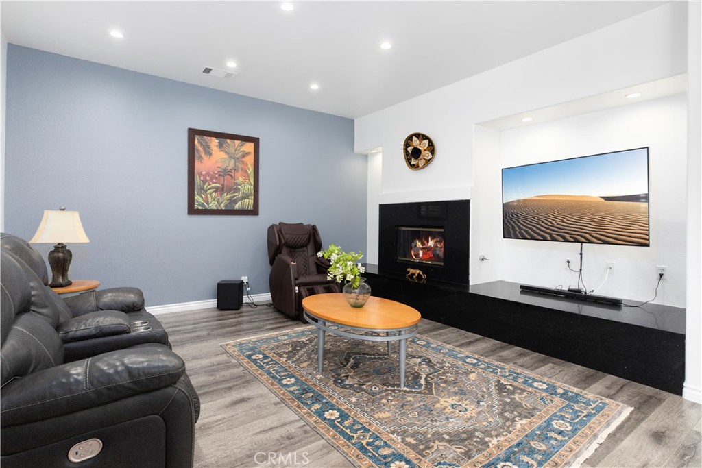 Furnished living room with gray reclining sofas, a black fireplace wall, and a patterned area rug.