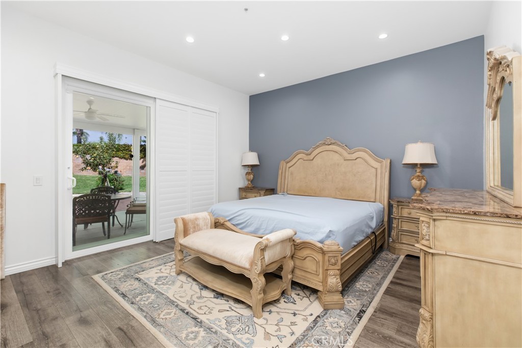 Furnished bedroom with ornate beige furniture, a blue-gray accent wall, and sliding glass doors to a garden patio.