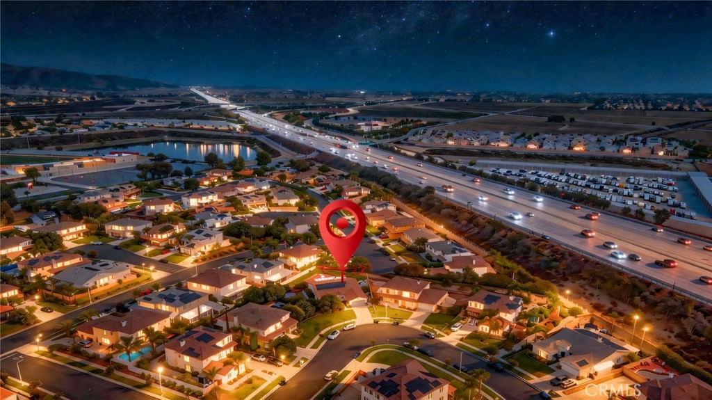 Nighttime aerial of homes beside a freeway, marked with a red pin.