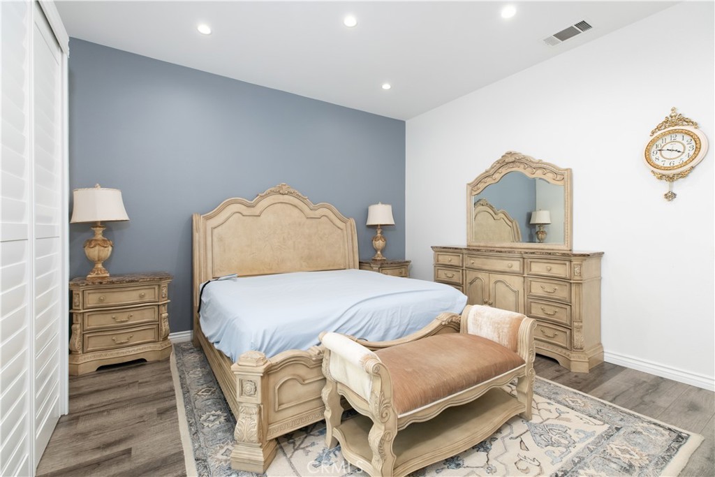 Bedroom with an ornate carved bed, matching furniture, blue accent wall, and patterned rug.