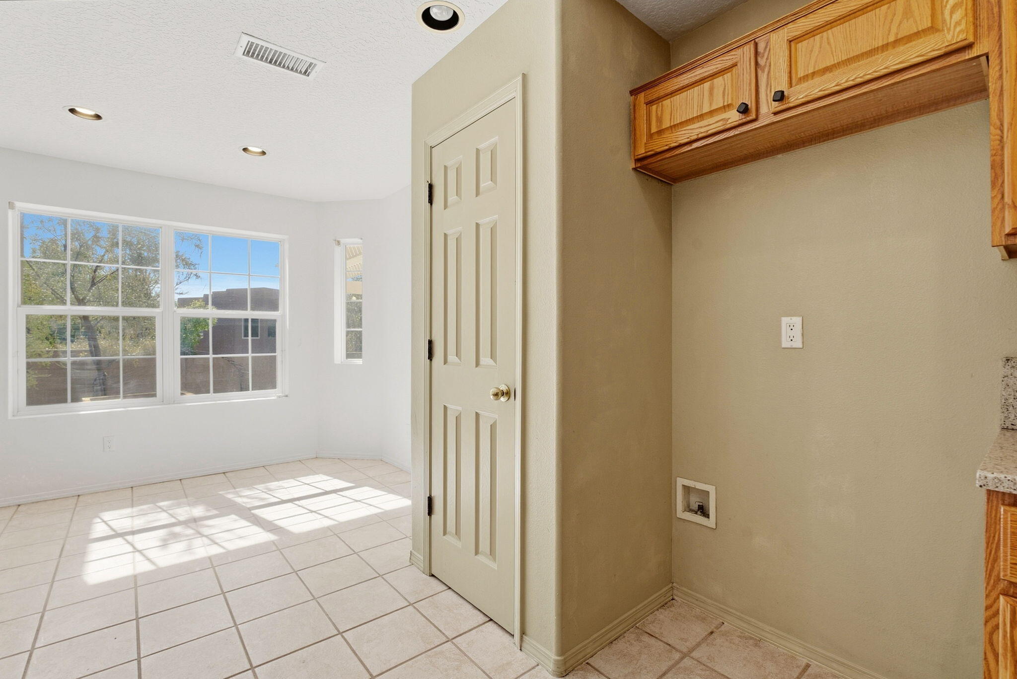 Bright tiled room with large windows and wood cabinets above a counter edge.