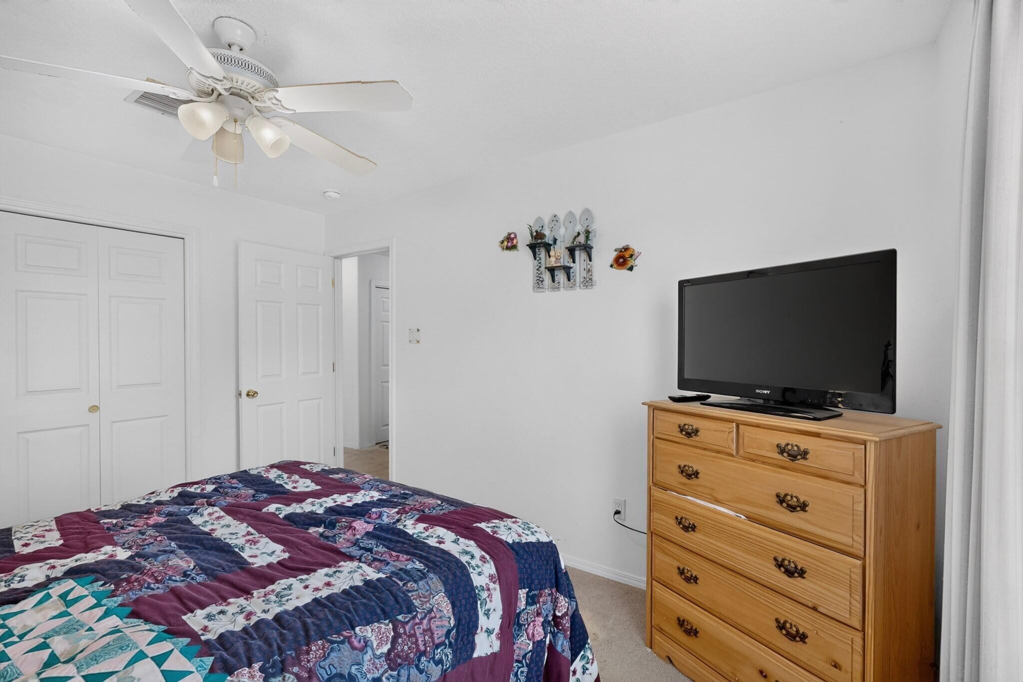 Bedroom with a colorful patchwork quilt and television on a wooden dresser.