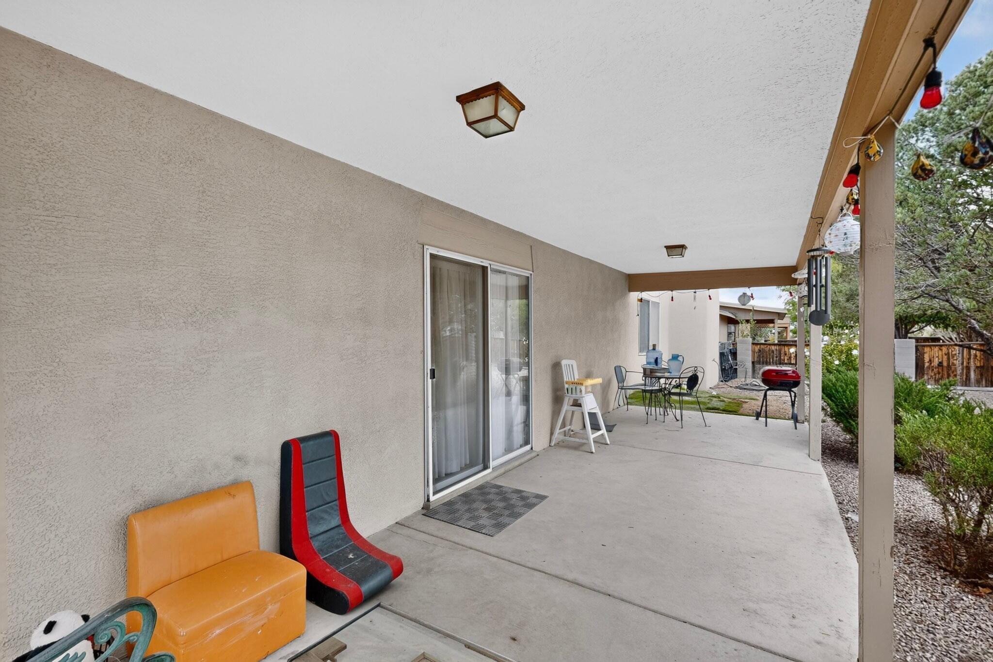 Covered patio with a sliding glass door, colorful lounge chairs, outdoor dining set, and barbecue grill.
