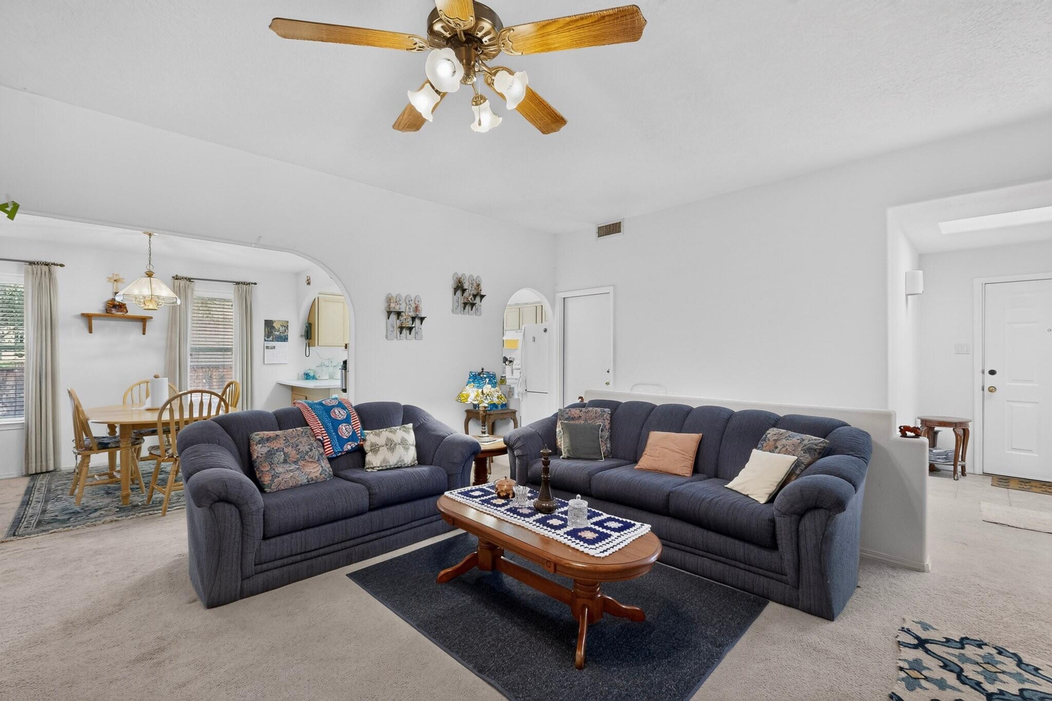 Living room with two dark blue sofas, a wooden coffee table, and an adjoining dining area.