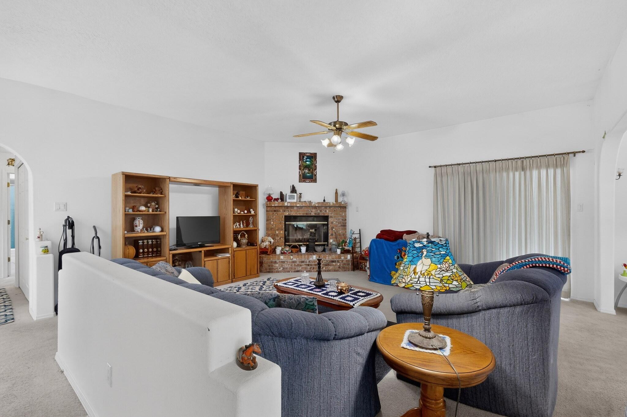 Living room with a brick fireplace, built-in shelving, and gray sectional seating.