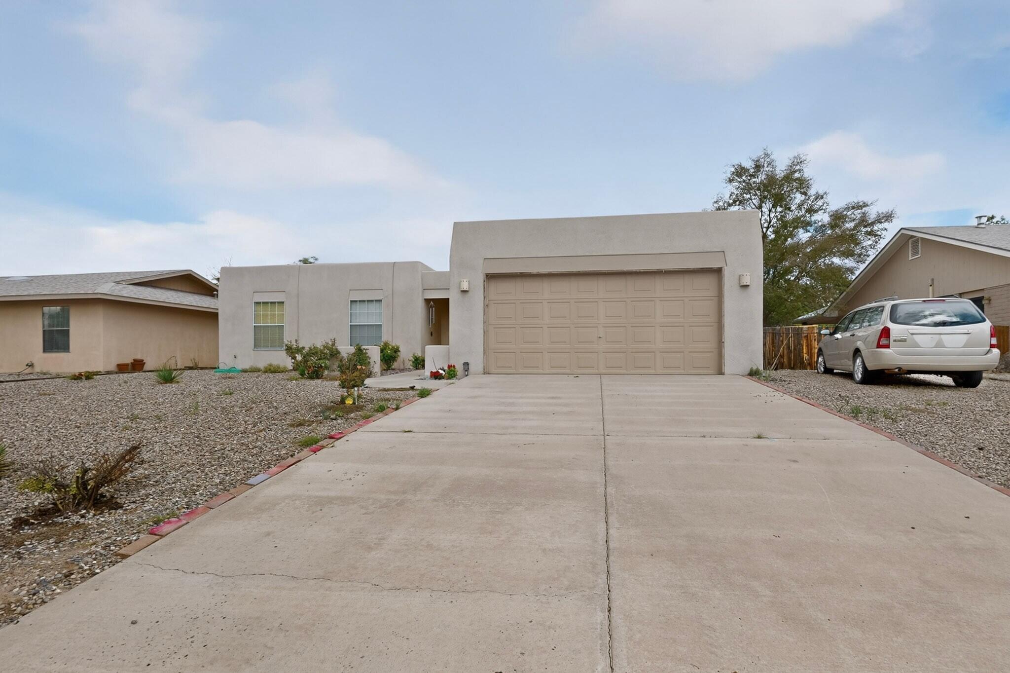 Single-story stucco home with a large attached garage and broad concrete driveway.