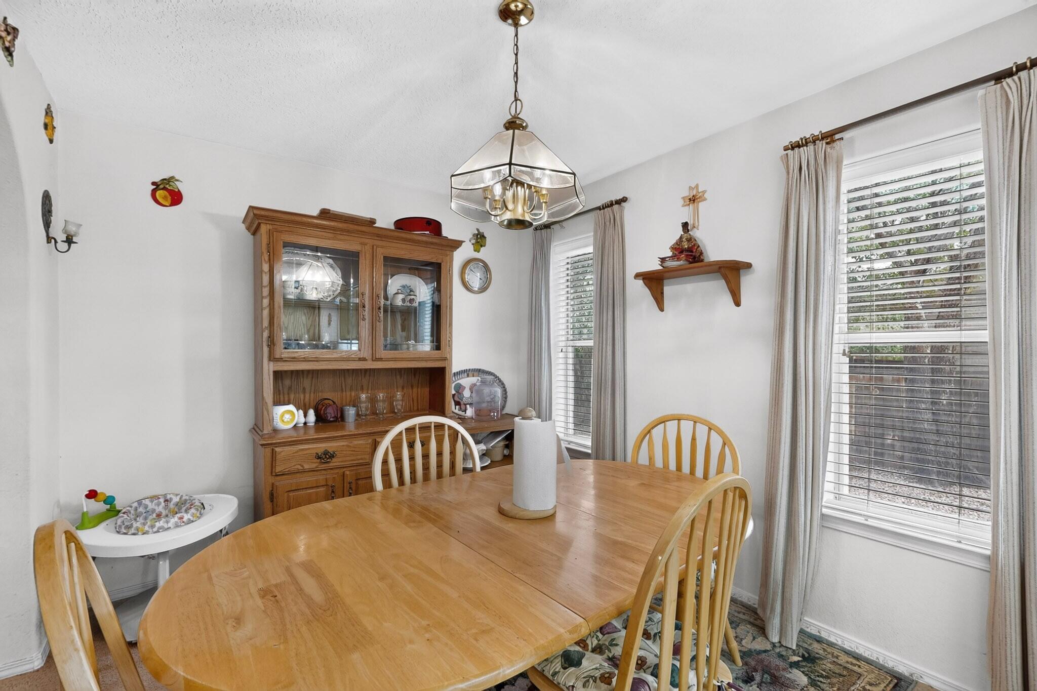 Dining room with an oval wooden table, matching chairs, and a wooden china cabinet.