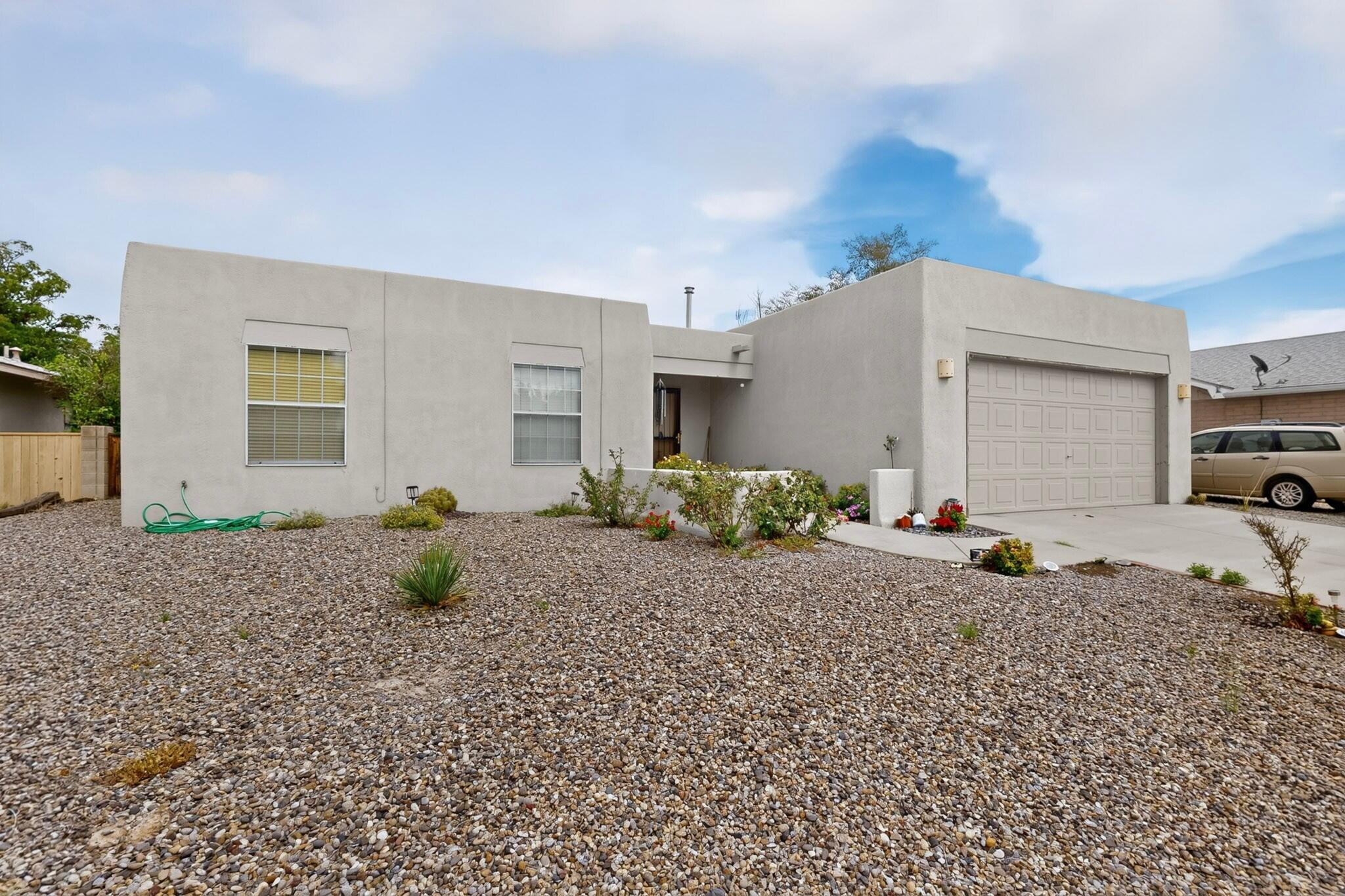 Single-story stucco home with a two-car garage and a gravel front yard.