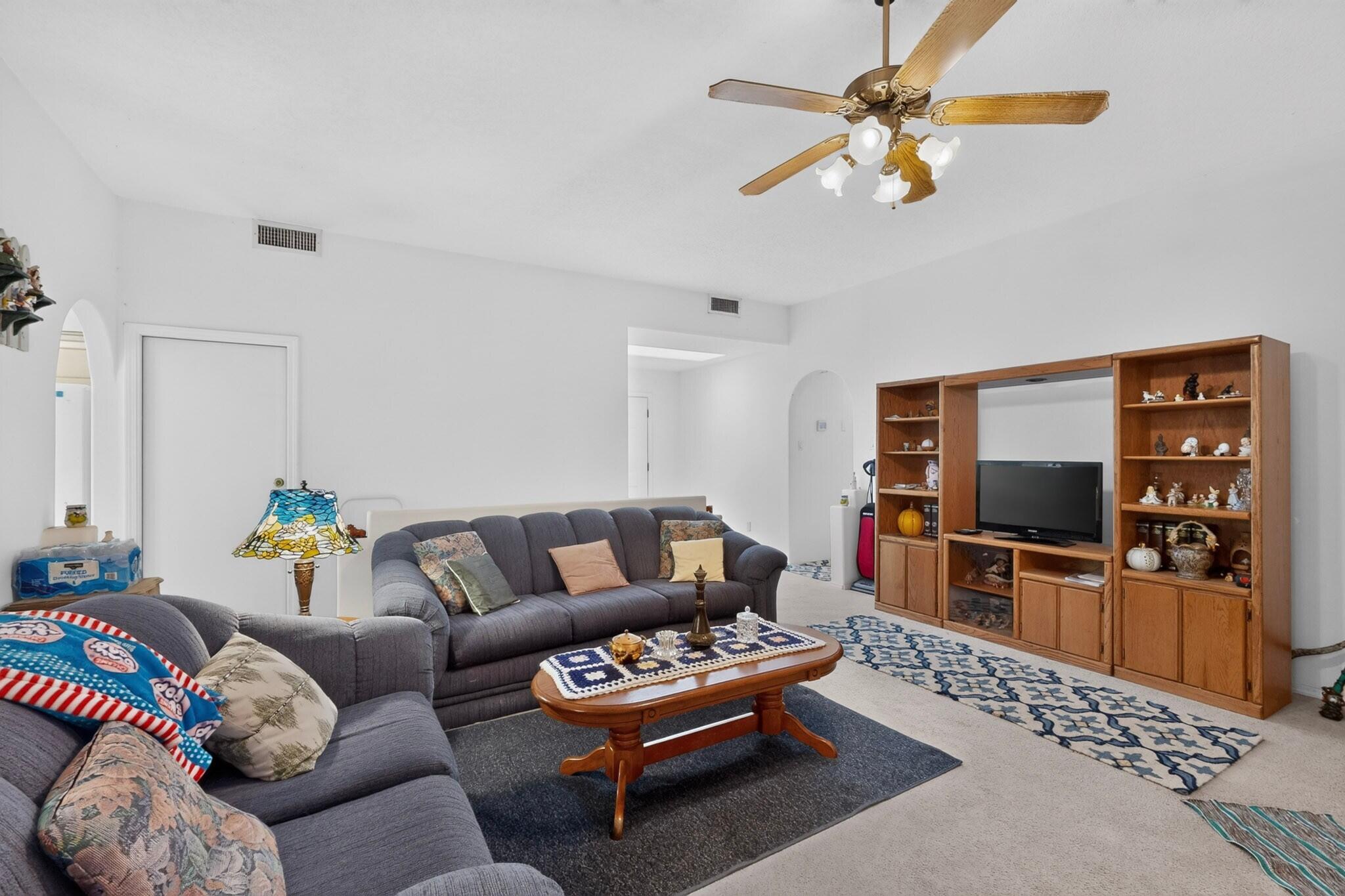 Living room with gray sectional sofas and a wooden entertainment center displaying a television and collectibles.