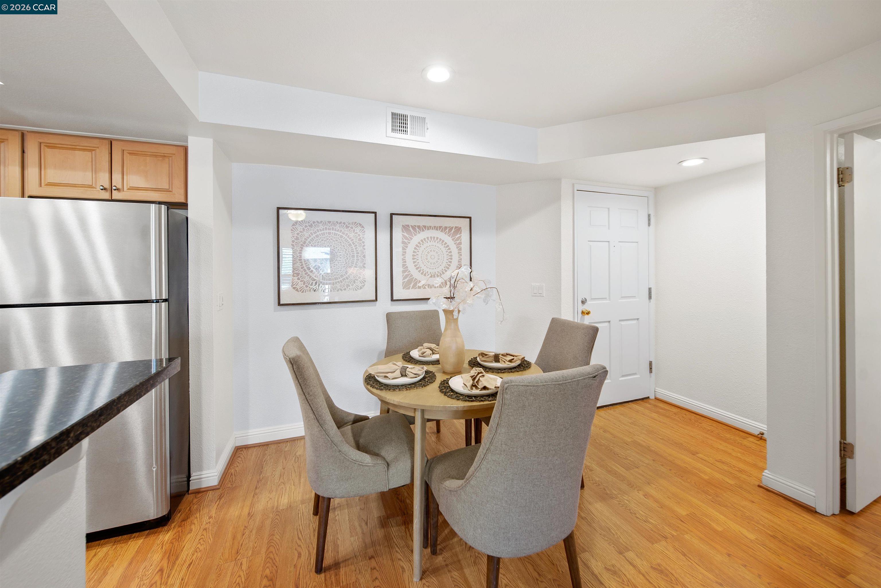 Dining area with a round table set for four beside a kitchen with stainless-steel appliances.