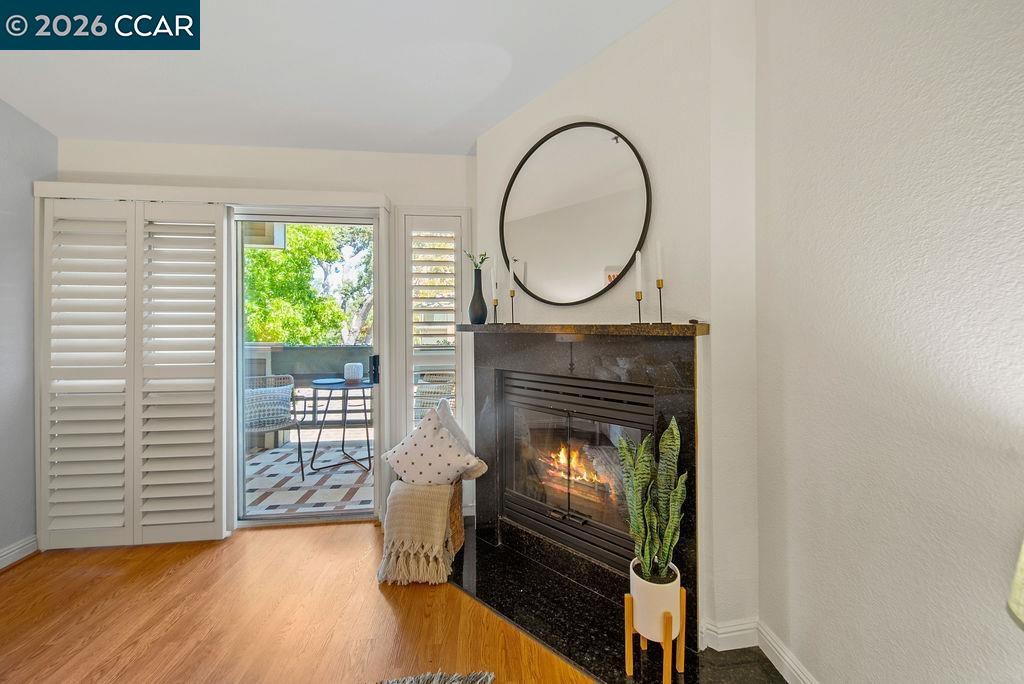 Living room with a lit fireplace beside a sliding glass door opening to a patio.