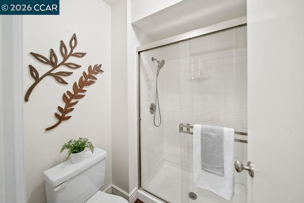 Bathroom with a glass-enclosed white-tiled shower and wooden branch wall decorations.