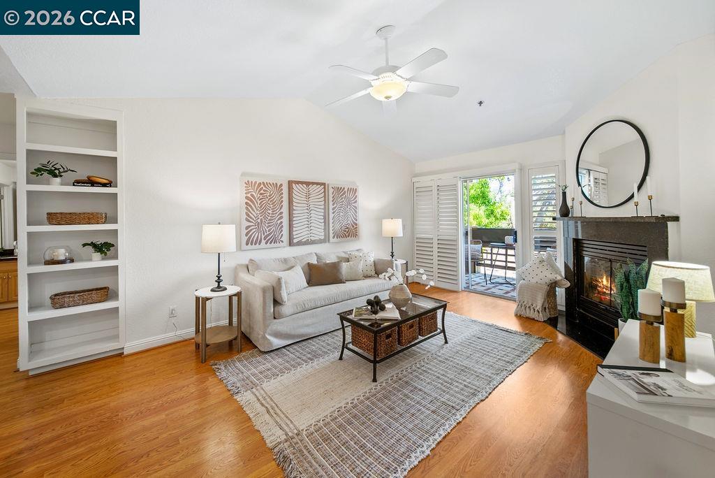 Living room with built-in shelves, a fireplace, hardwood floors, and sliding doors to a patio.