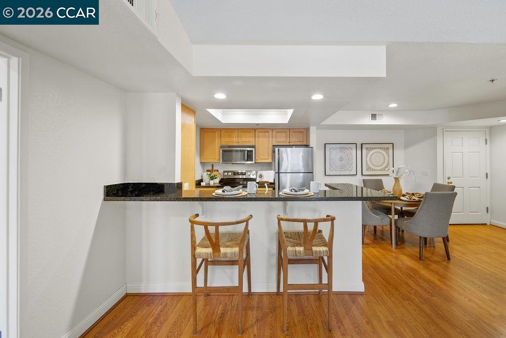 Open-plan kitchen and dining area with a granite breakfast bar and warm wood floors.