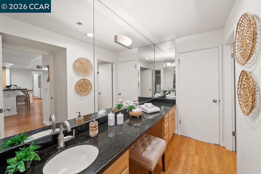 Bathroom with a long black stone double vanity, large mirrors, and wood cabinetry.