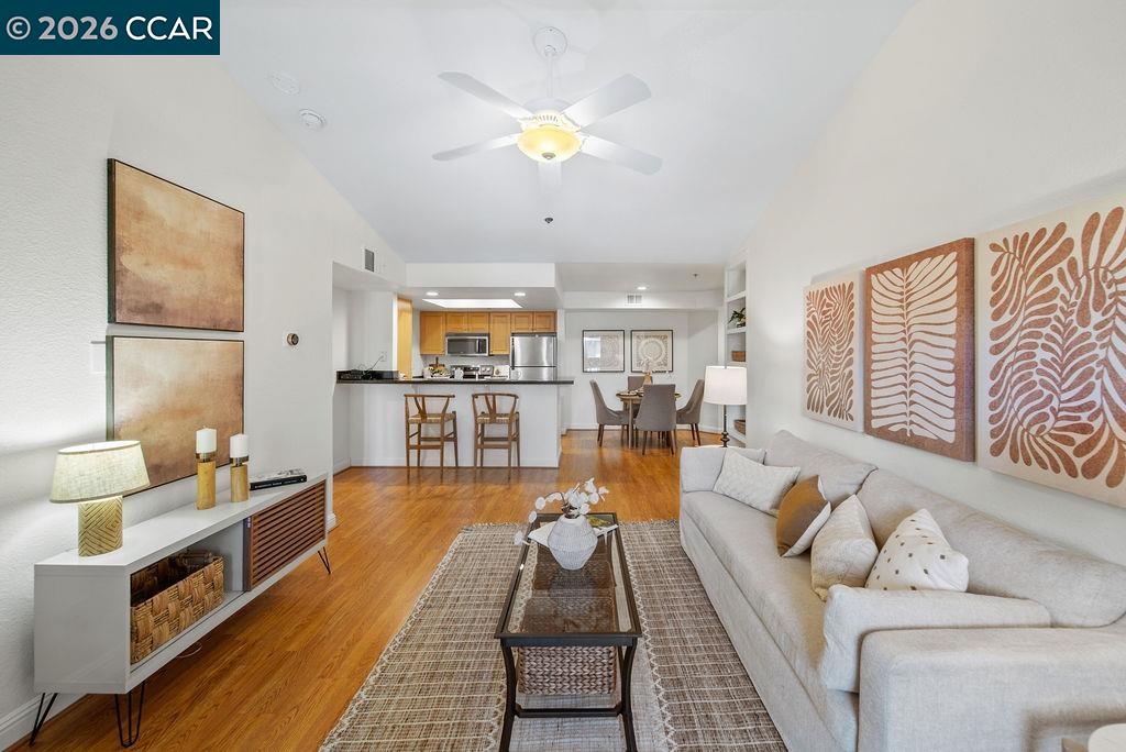Living room with a white sofa, hardwood floors, and an open kitchen with a breakfast bar.