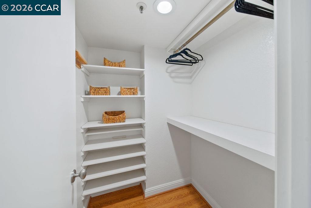 Walk-in closet with white shelving, woven baskets, hangers, and a long counter.