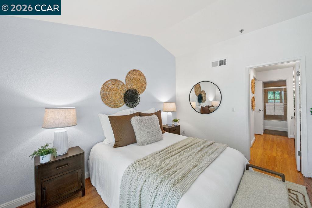Bedroom with a white bed, woven wall decor, and an open doorway to the bathroom.