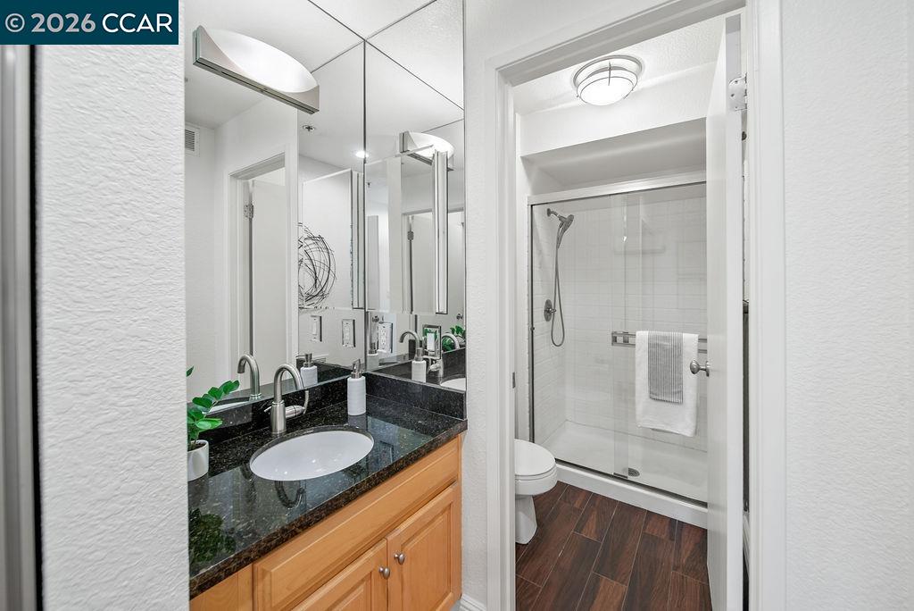 Bathroom with a black granite vanity and glass-enclosed shower.