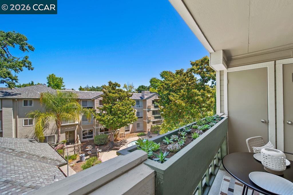 Apartment balcony with succulent planter and seating overlooking a landscaped courtyard.