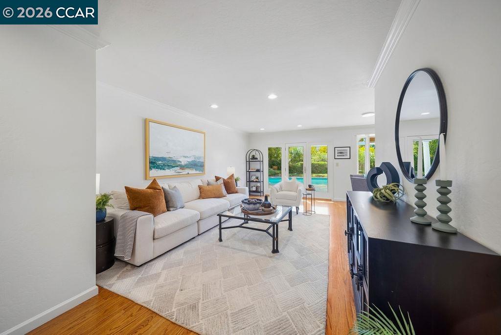 Furnished living room with a white sectional and glass doors overlooking a swimming pool.
