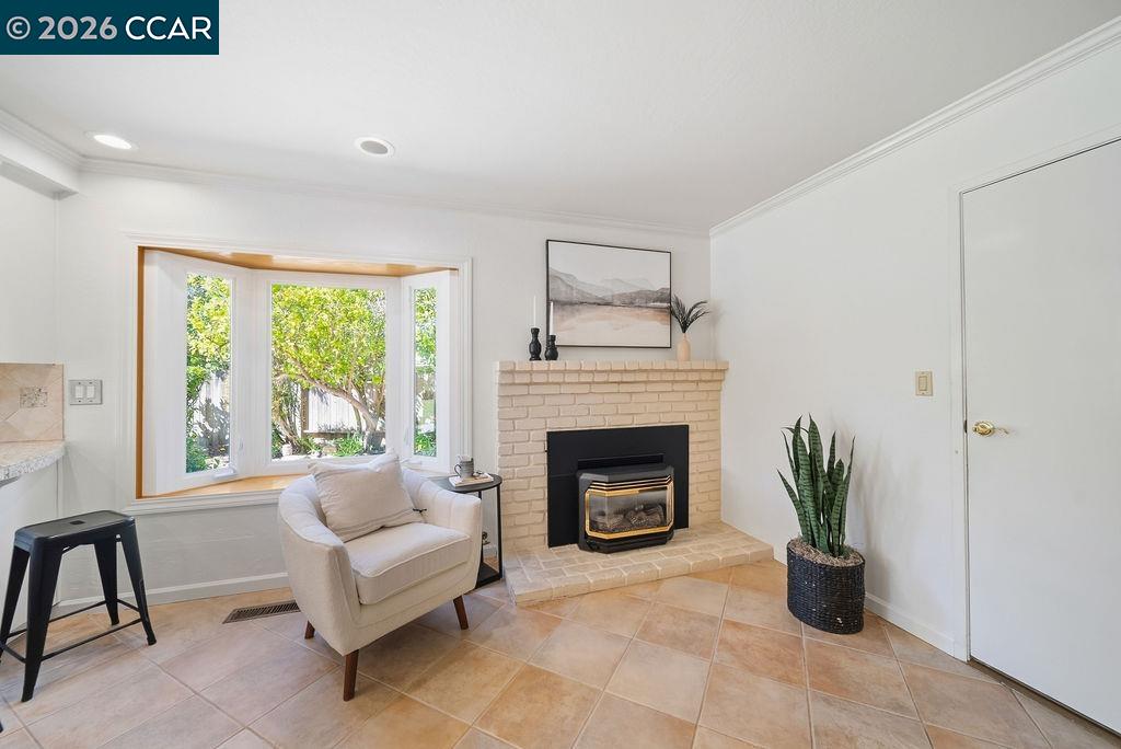 Living room with a cream brick fireplace, bay window, and white armchair.