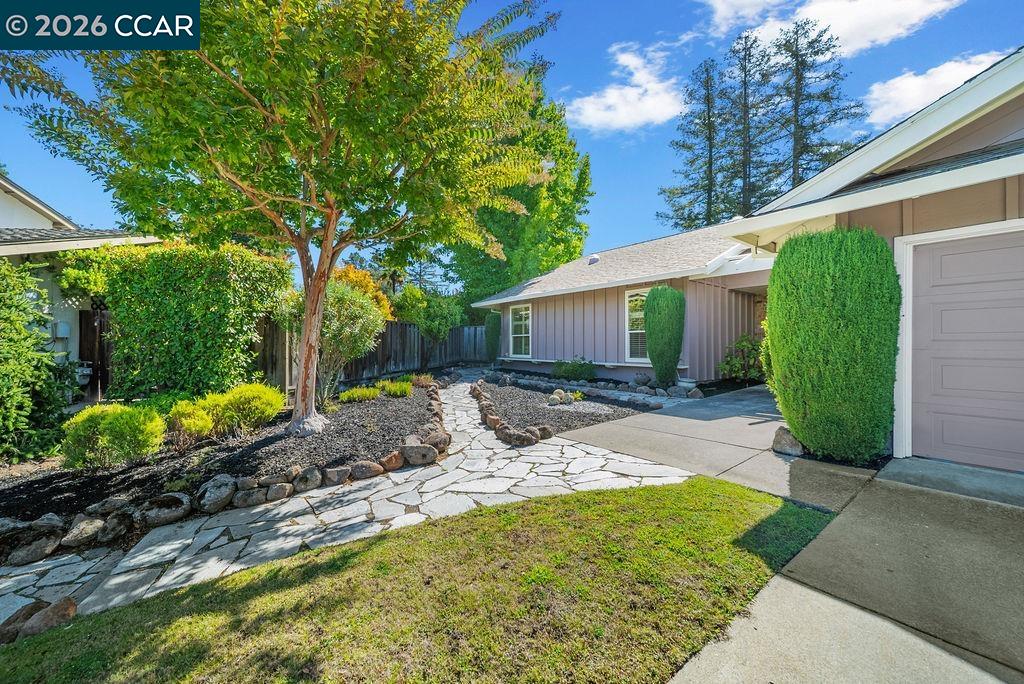 Home exterior with a stone walkway, landscaped yard, and attached garage.