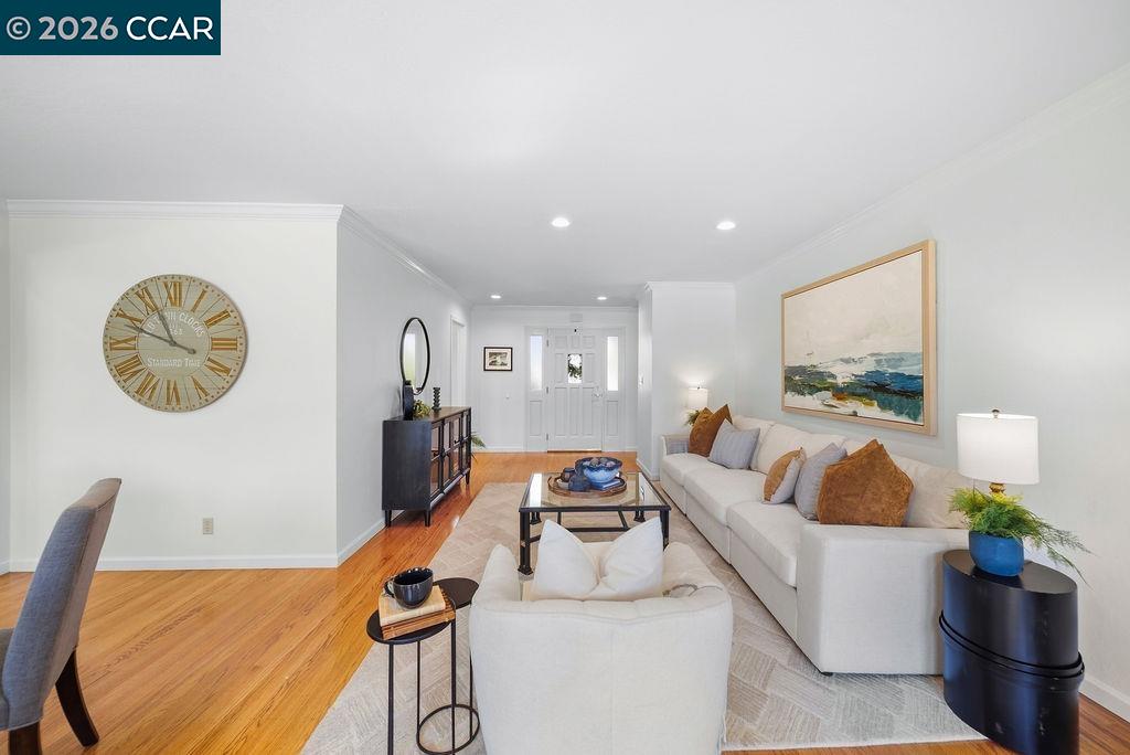 Staged living room with white sofas, hardwood floors, and coastal artwork.