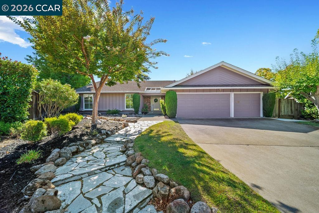 Single-story home with a two-car garage, landscaped yard, and stone walkway to the entrance.