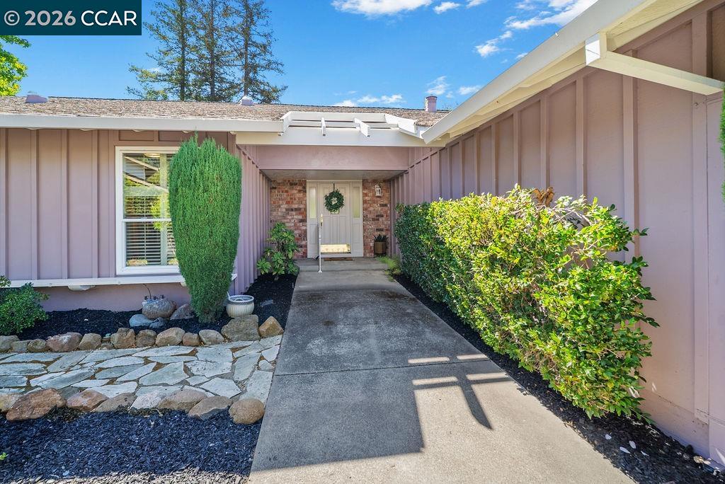 Home entrance with a covered porch, brick facade, and landscaped walkway.