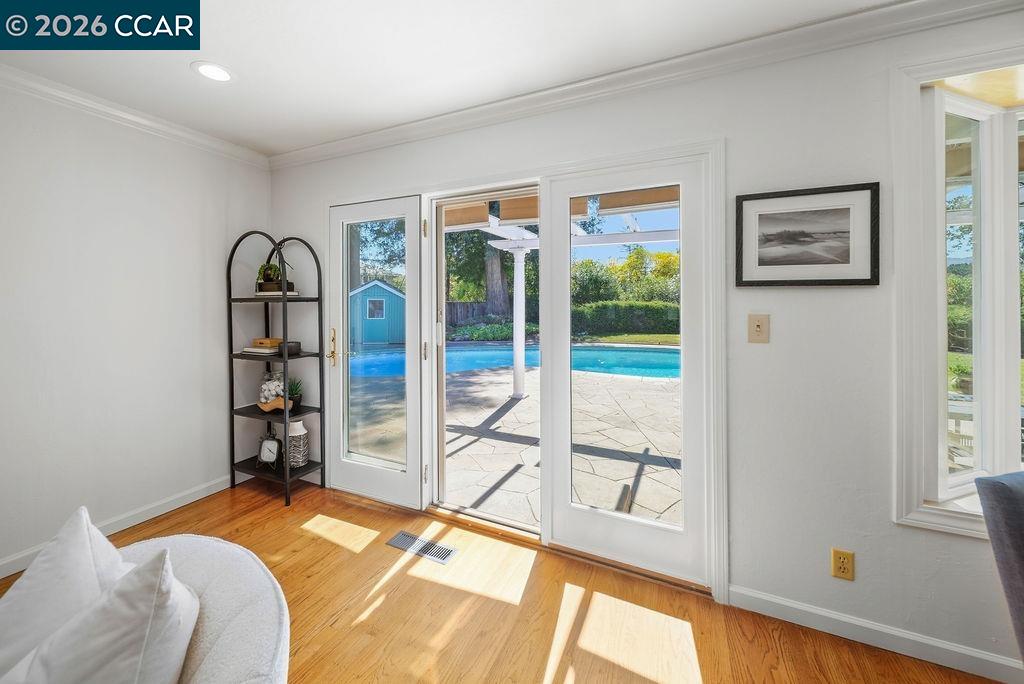 Sitting room with hardwood floors and French doors opening to a patio and swimming pool.