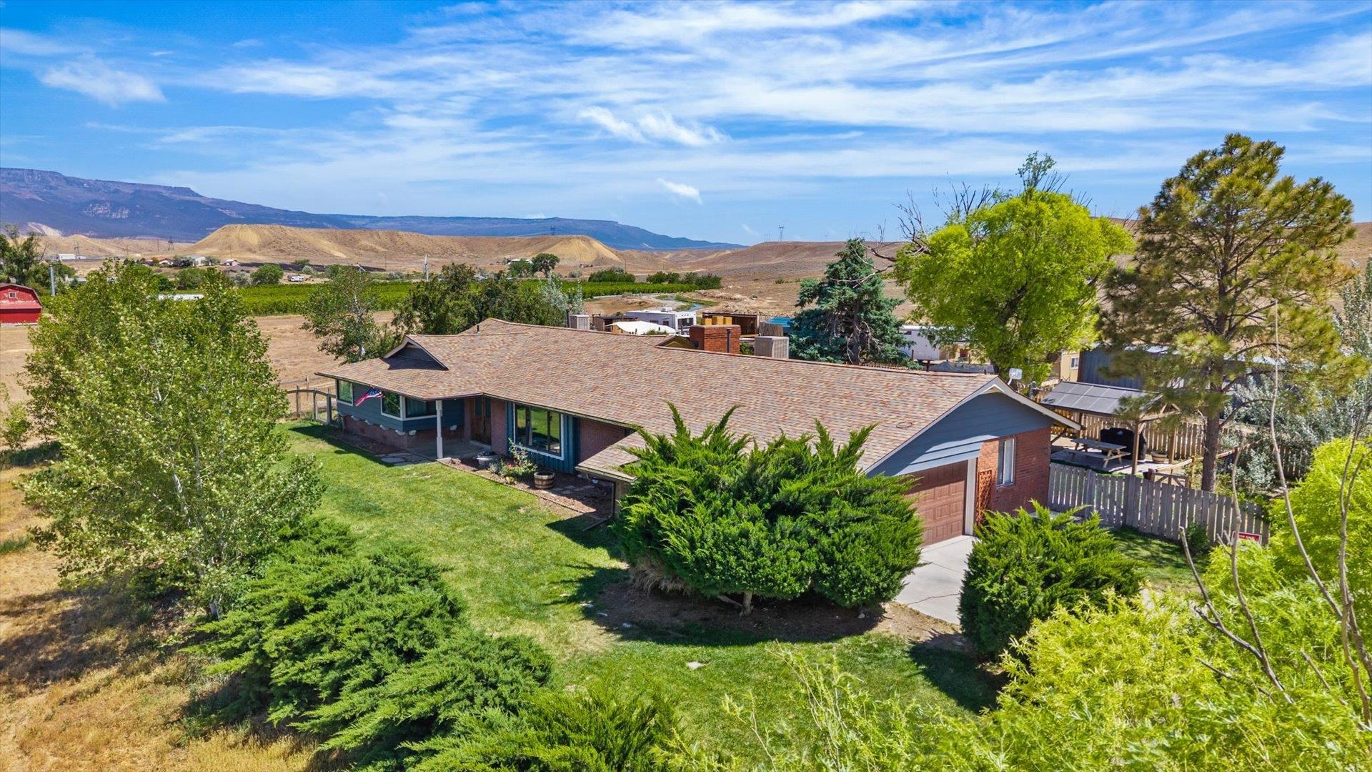 Single-story ranch home with an attached garage, green lawn, and mountain views.