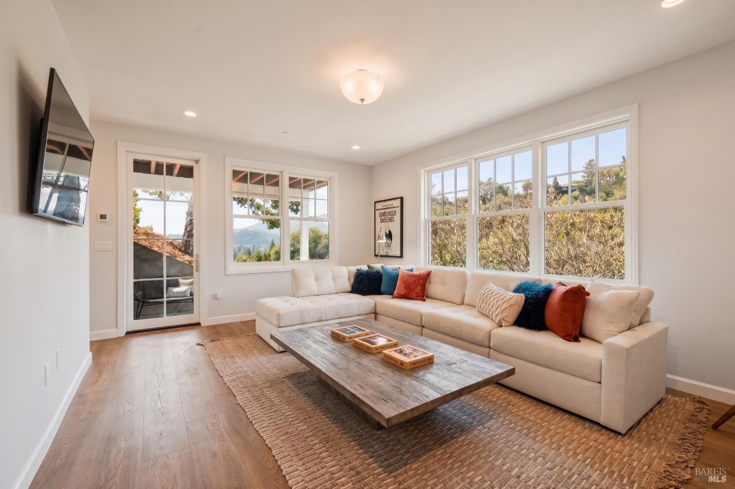 Living room with a cream sectional, rustic coffee table, and large windows overlooking trees and hills.