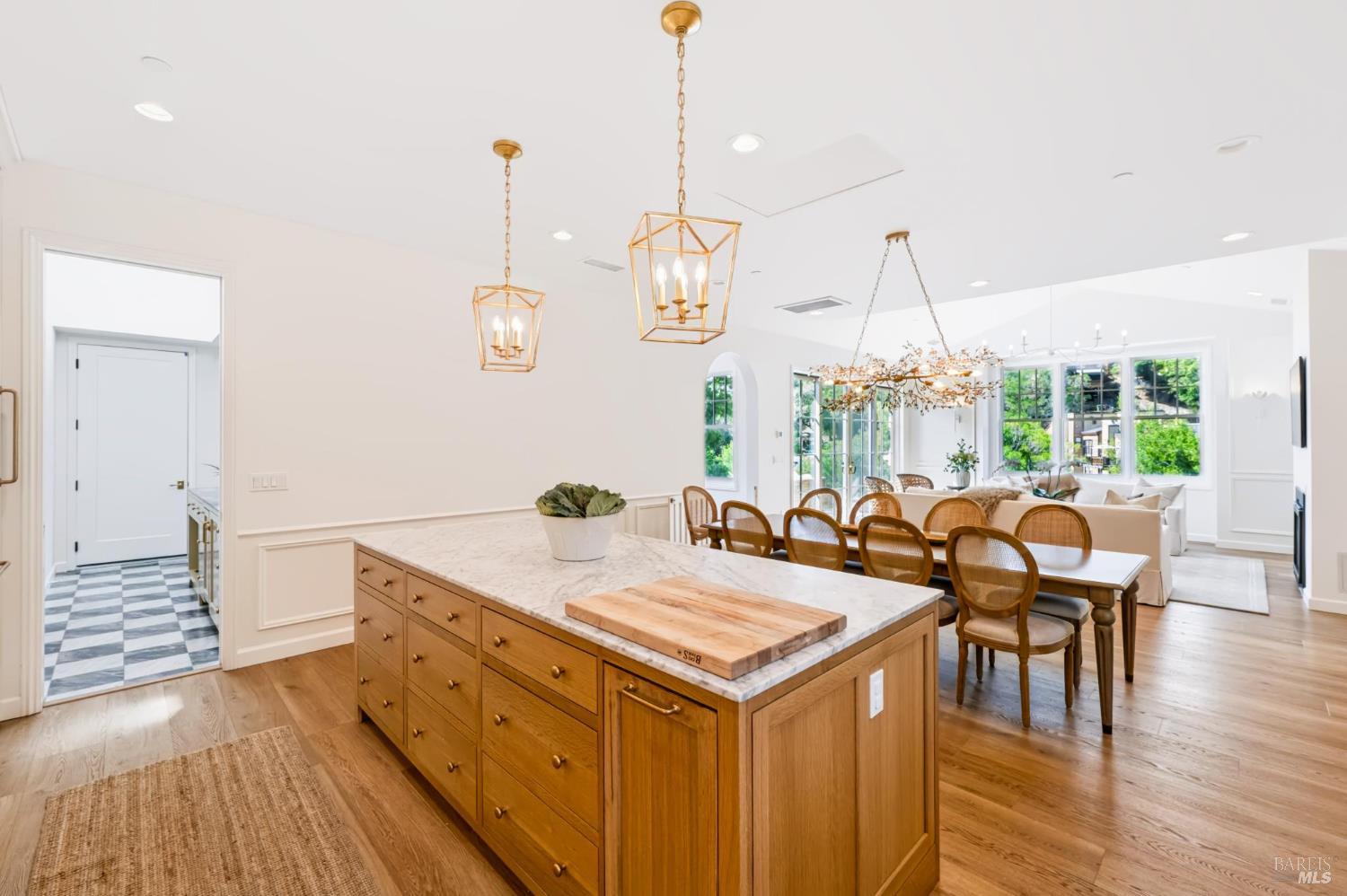 Open-plan kitchen and dining area with a marble-topped island and brass pendant lights.