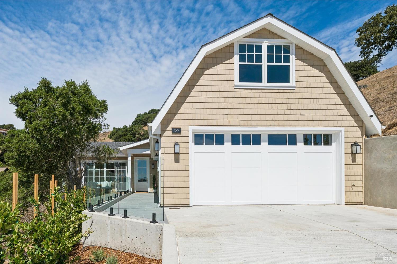 Home at 187 Sacramento Avenue with a barn-style facade, white garage door, and glass-sided walkway.