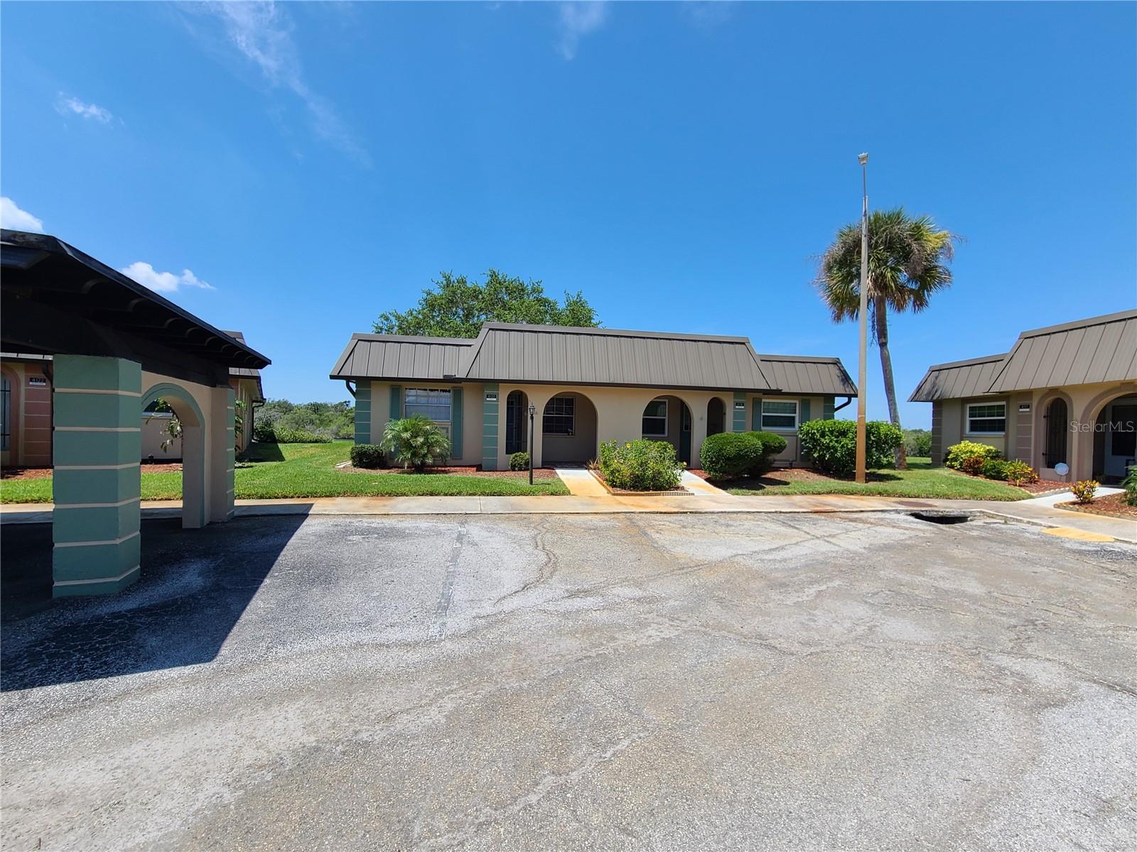Low-rise property with covered entrances, landscaped frontage, and a palm tree beside the parking area.