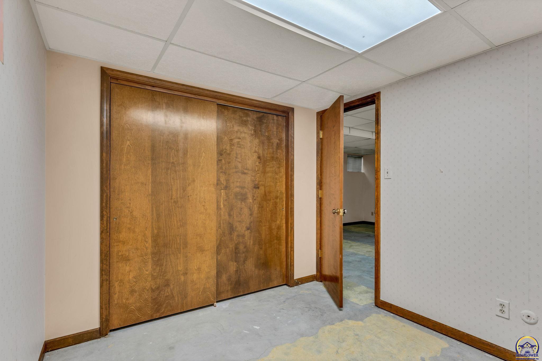 Empty room with wood sliding closet doors and an open doorway to an adjoining room.