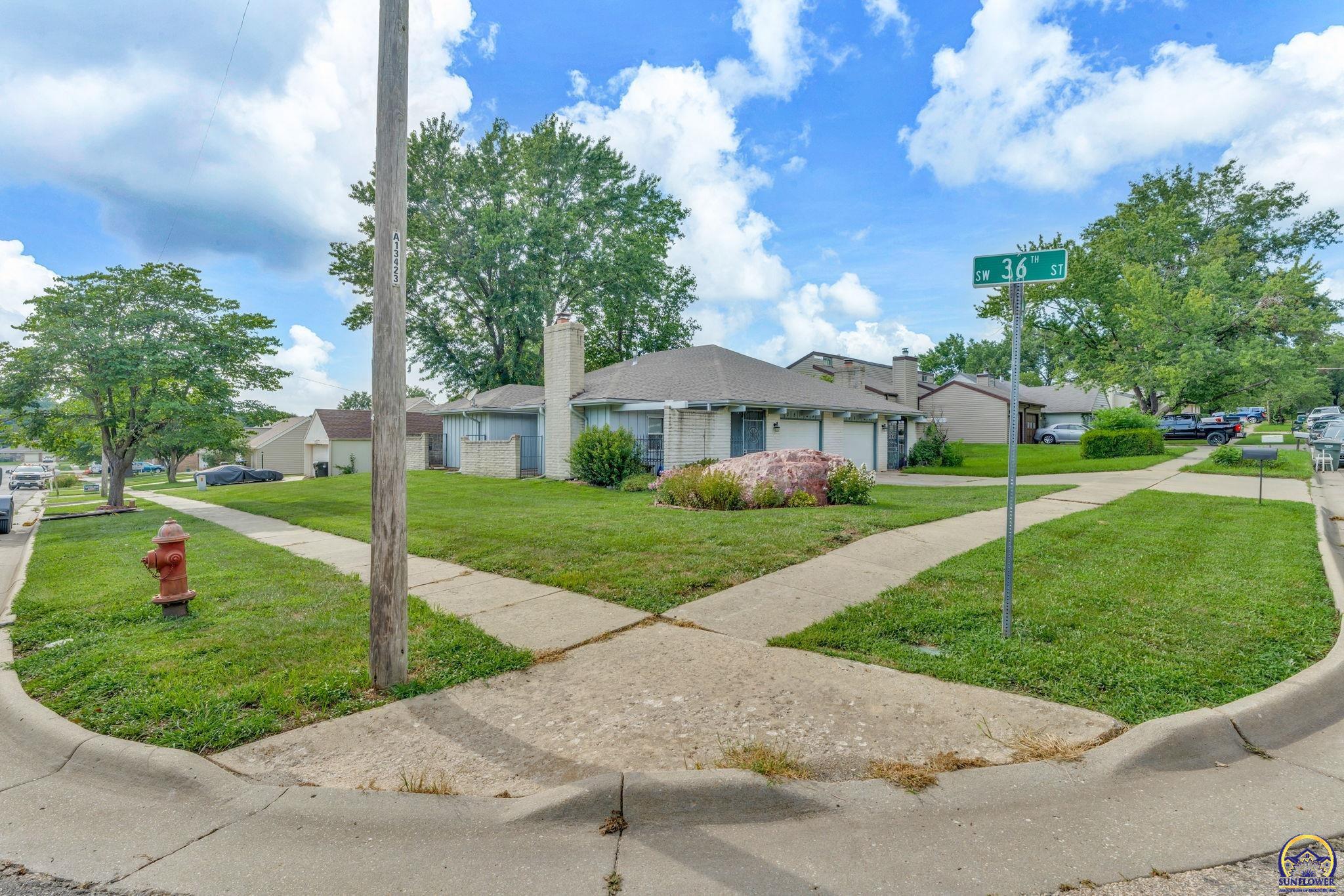 Single-story brick home on a grassy corner lot, viewed beside the SW 36th ST sign.