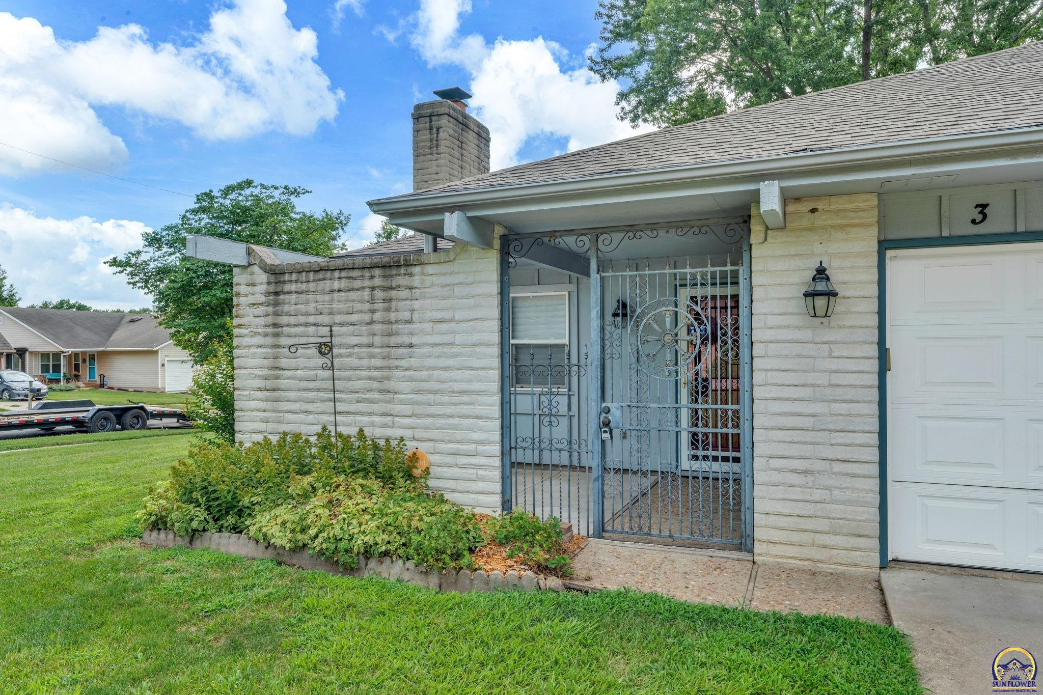 Stone-front home entry with an ornate metal security gate beside a white garage.