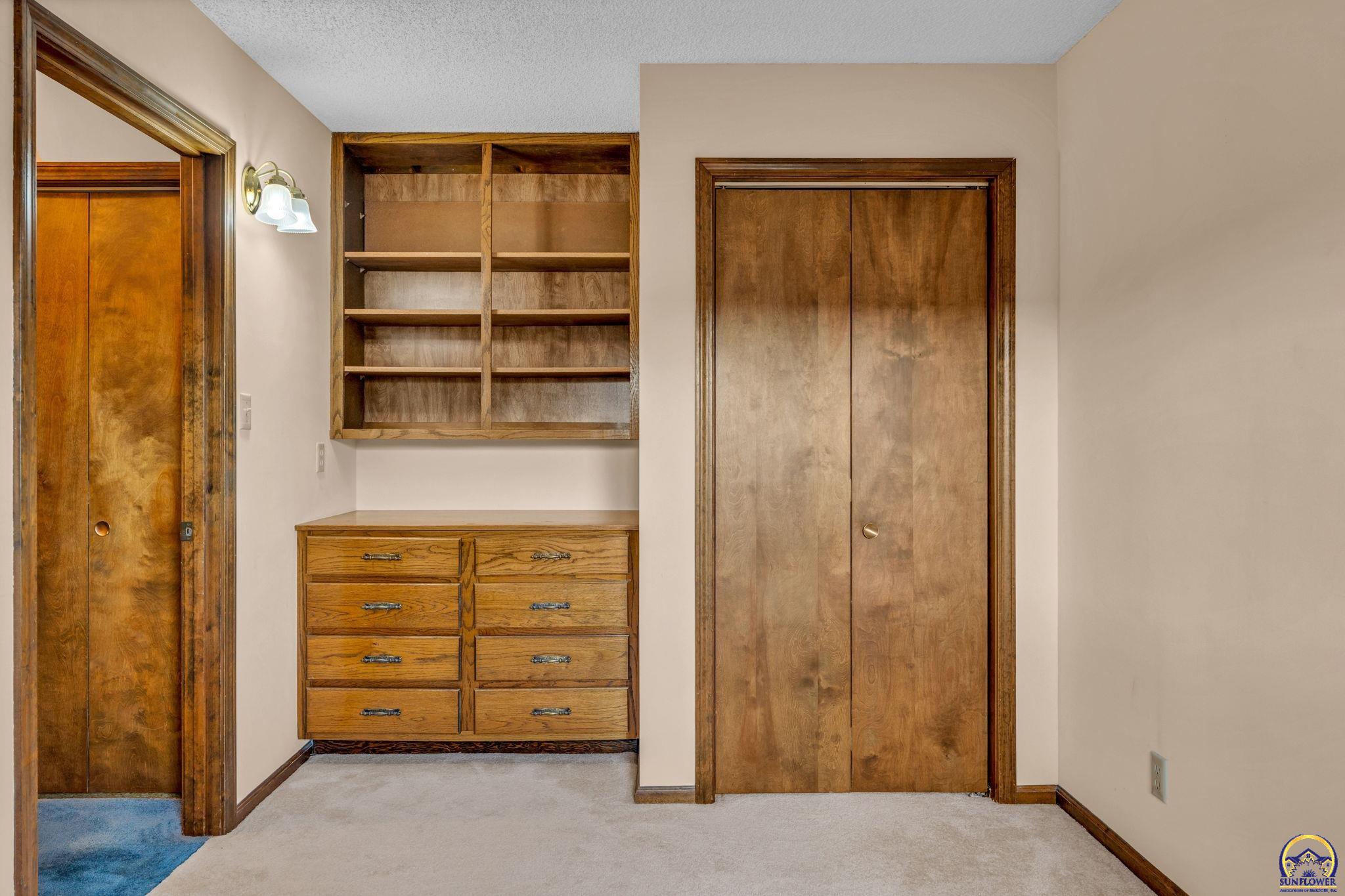 Bedroom with built-in oak drawers and shelves between two wood closet doors.