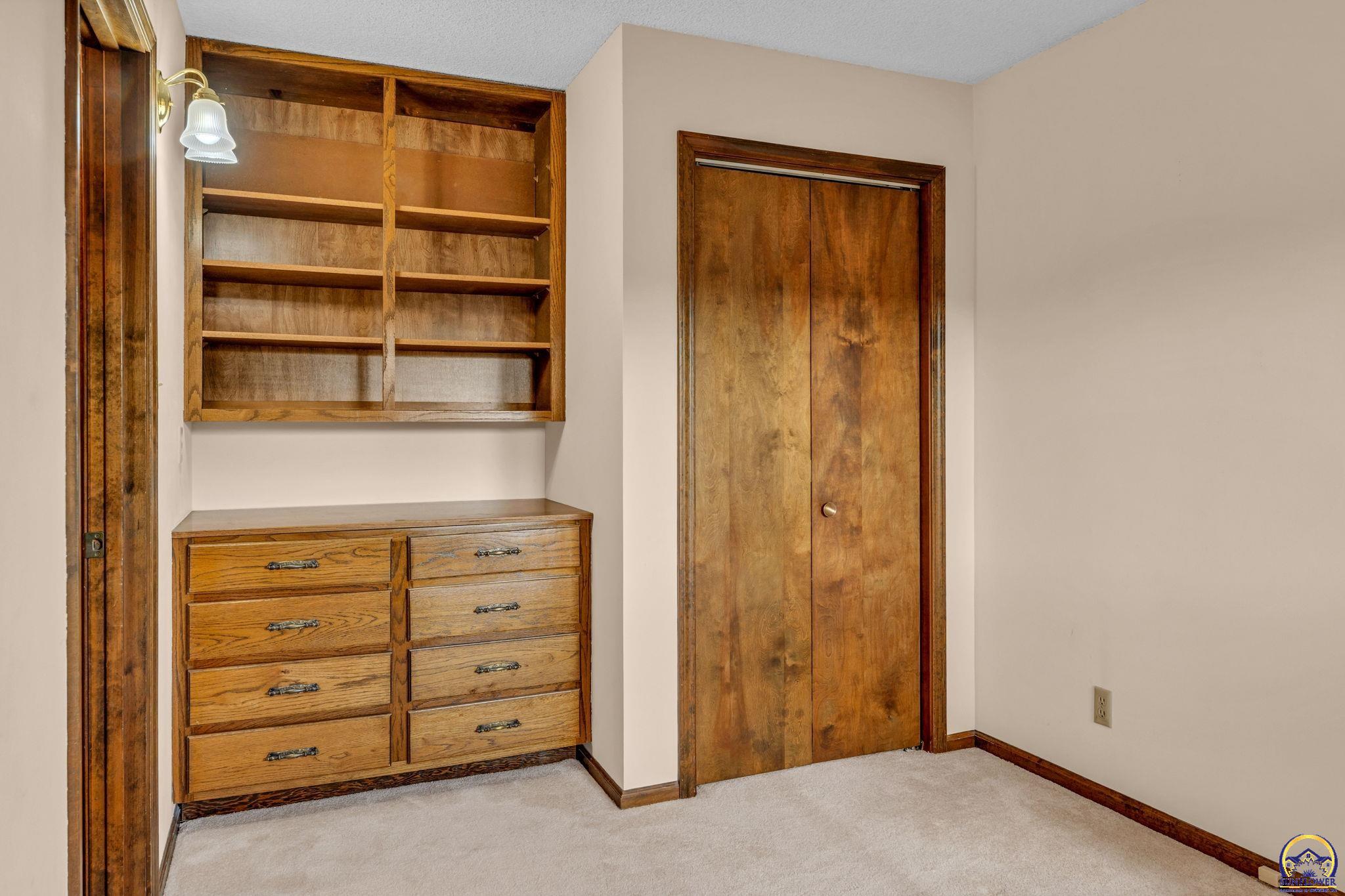 Built-in wooden shelves and dresser beside sliding closet doors in an empty bedroom.