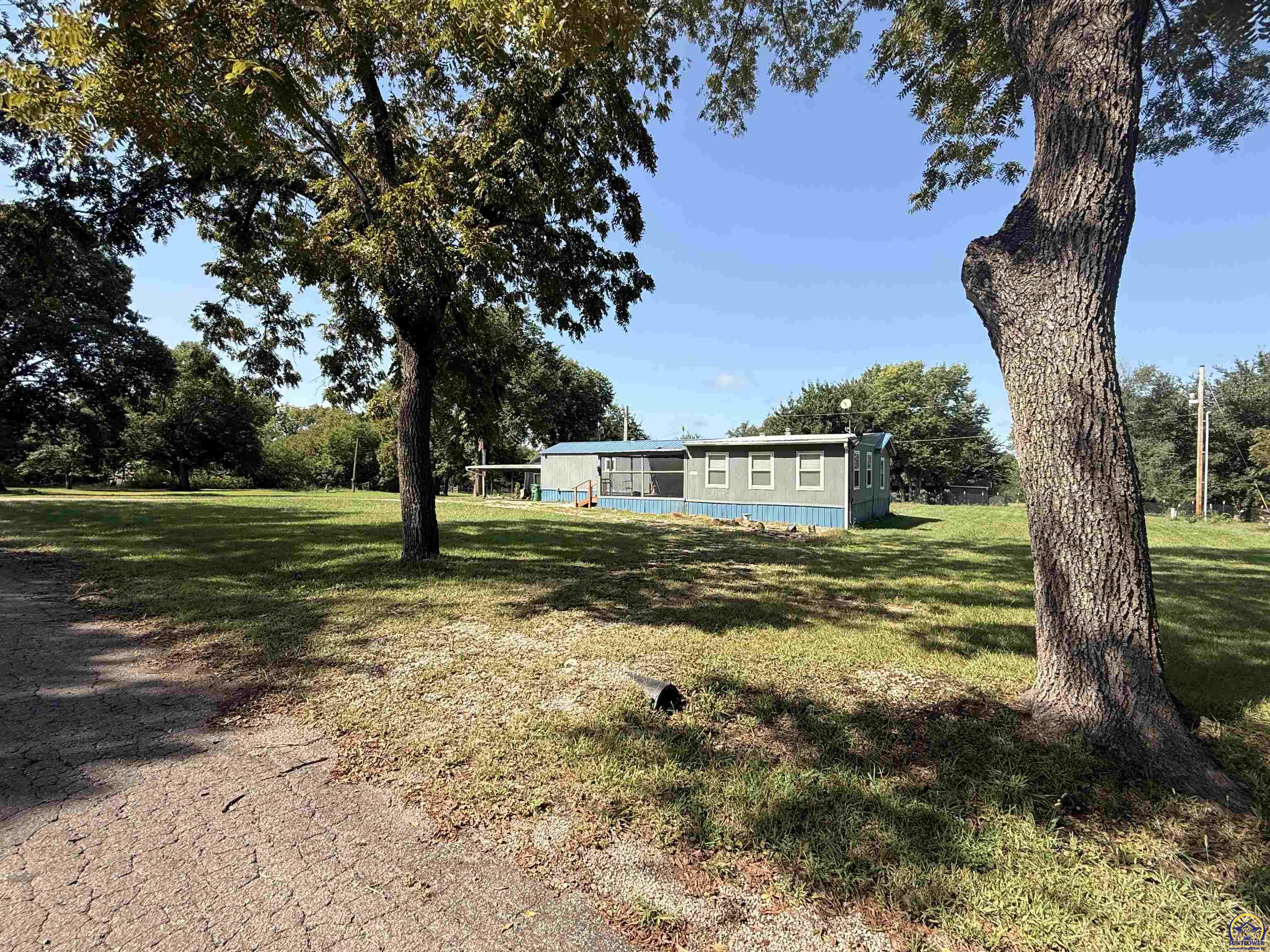 Single-story gray home with blue trim on a spacious, tree-shaded lawn.